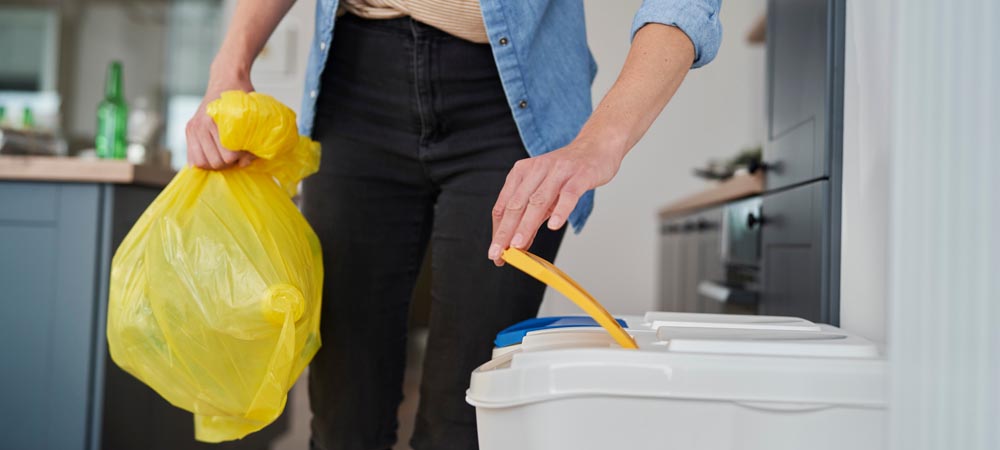 Sac en plastique jaune jeté dans la poubelle de recyclage